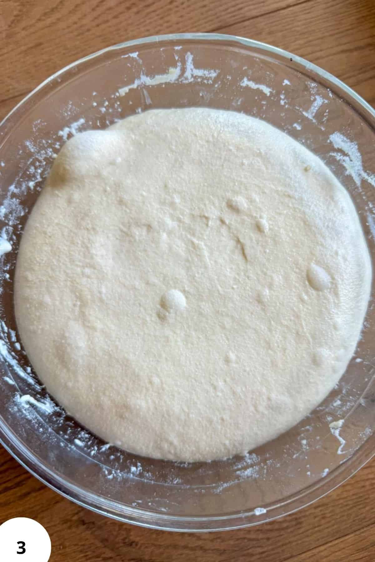 Close-up of sourdough starter fermenting in a glass bowl.