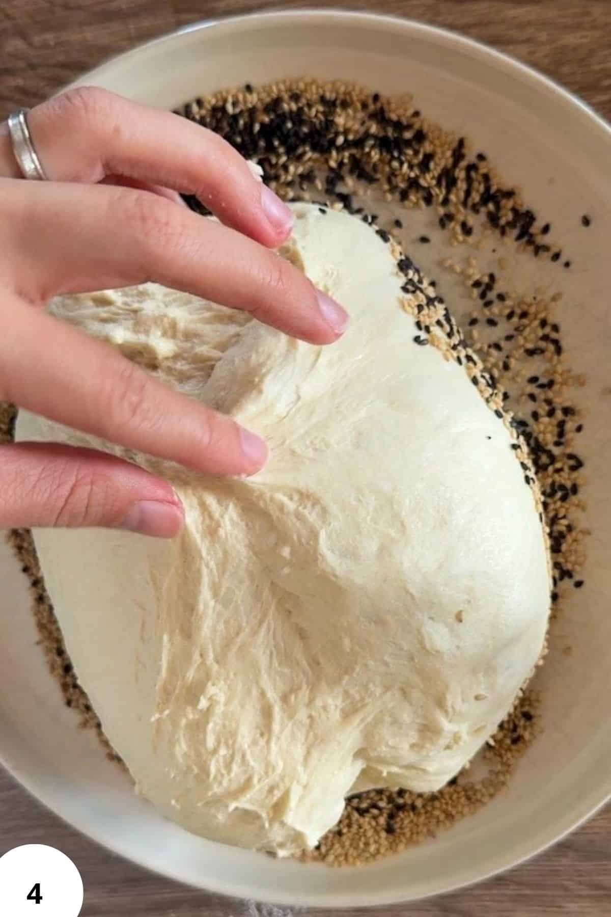 Hands performing stretch and fold technique for sourdough bread dough.