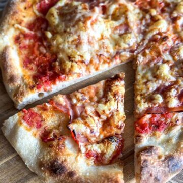 Close-up of Neapolitan-style sourdough pizza slices with cheese and toppings.