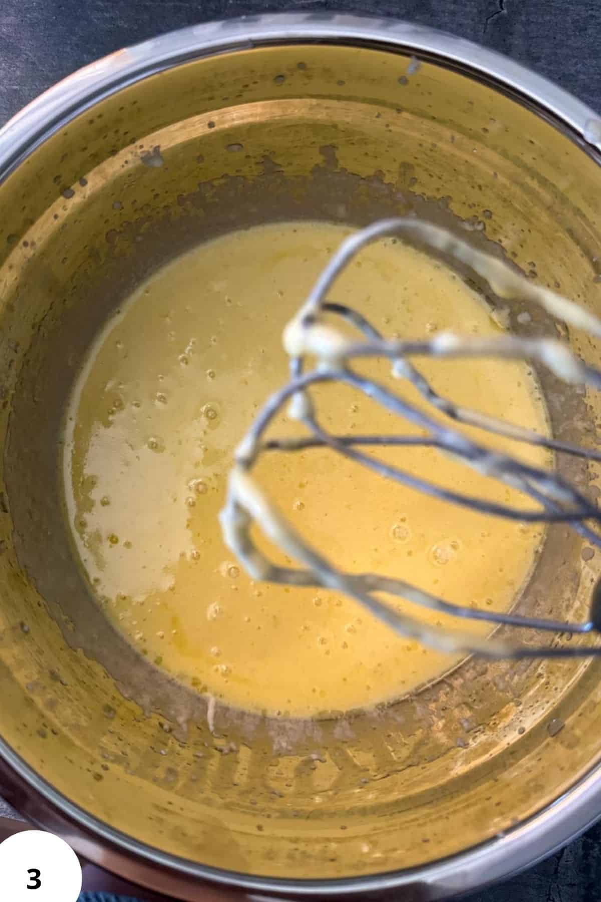 Mixing dough with a whisk in a metal bowl for stretch and fold technique.
