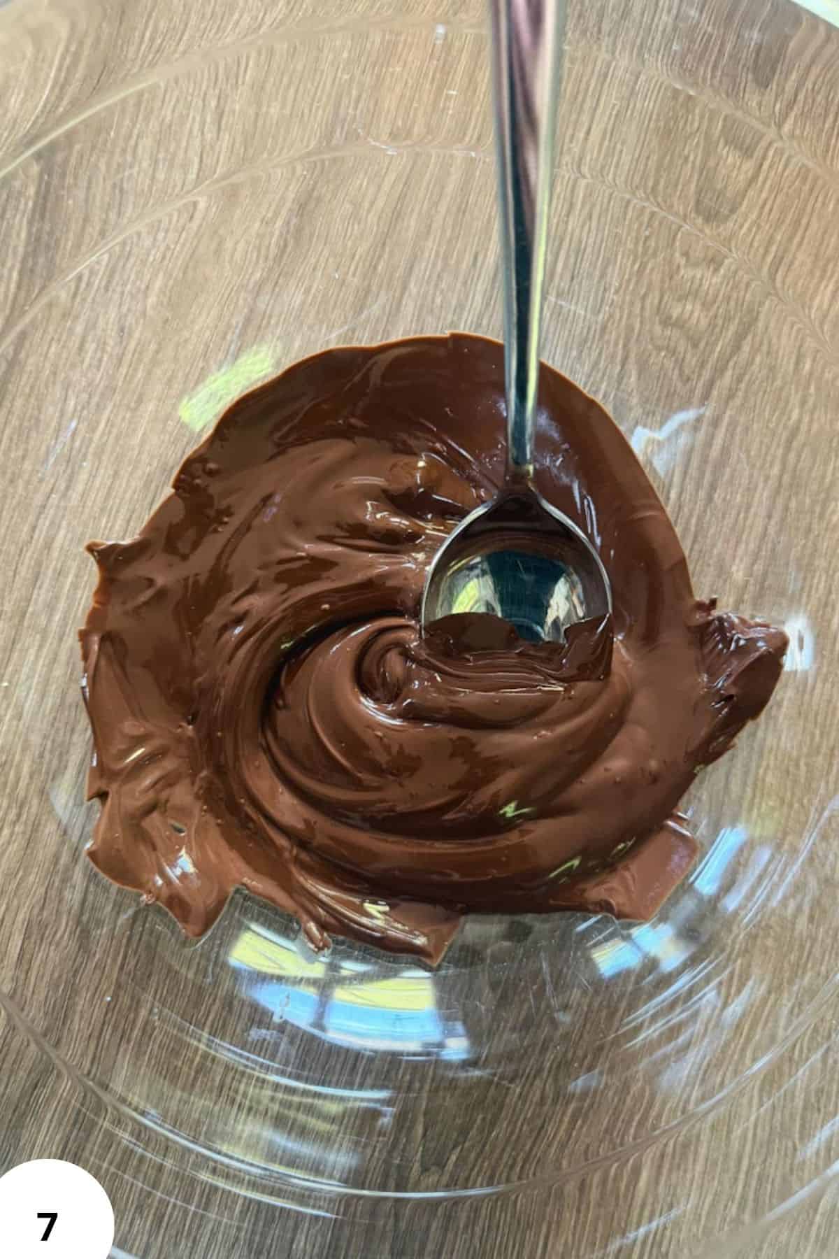Chocolate dough being folded in a glass bowl for bread baking process.