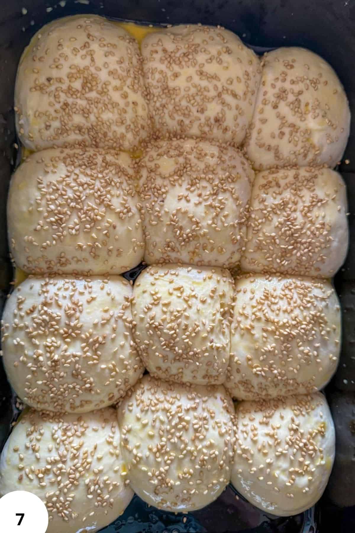 Freshly proofed dough balls topped with sesame seeds, ready for baking.