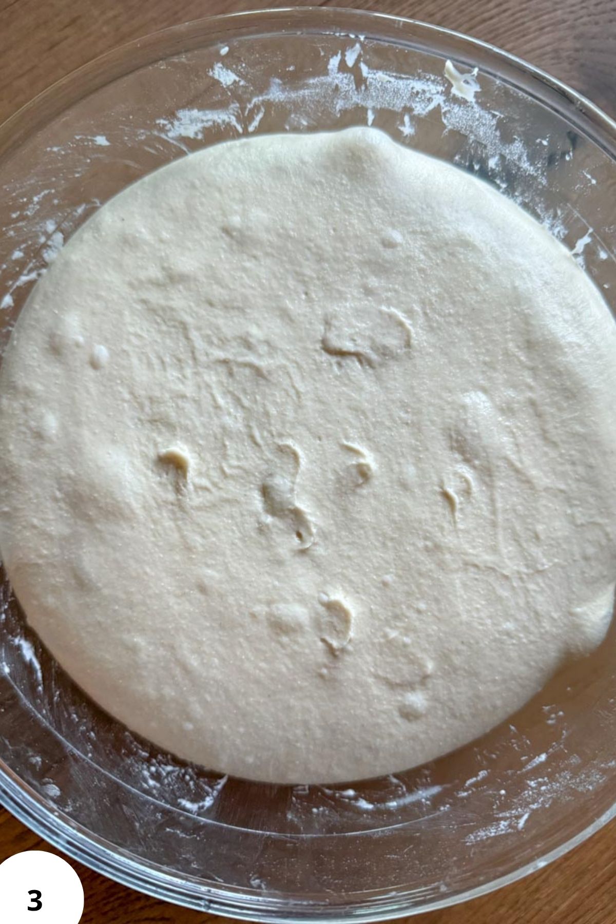 Fermented sourdough pizza dough in a glass bowl ready for baking.