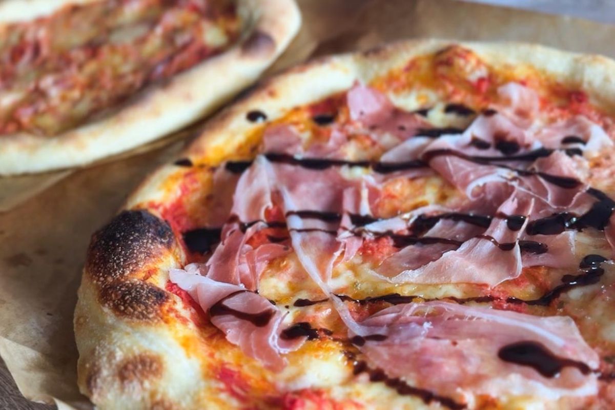 Close-up of sourdough pizza topped with prosciutto and balsamic glaze.
