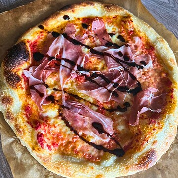 Close-up of sourdough pizza topped with prosciutto and balsamic glaze.