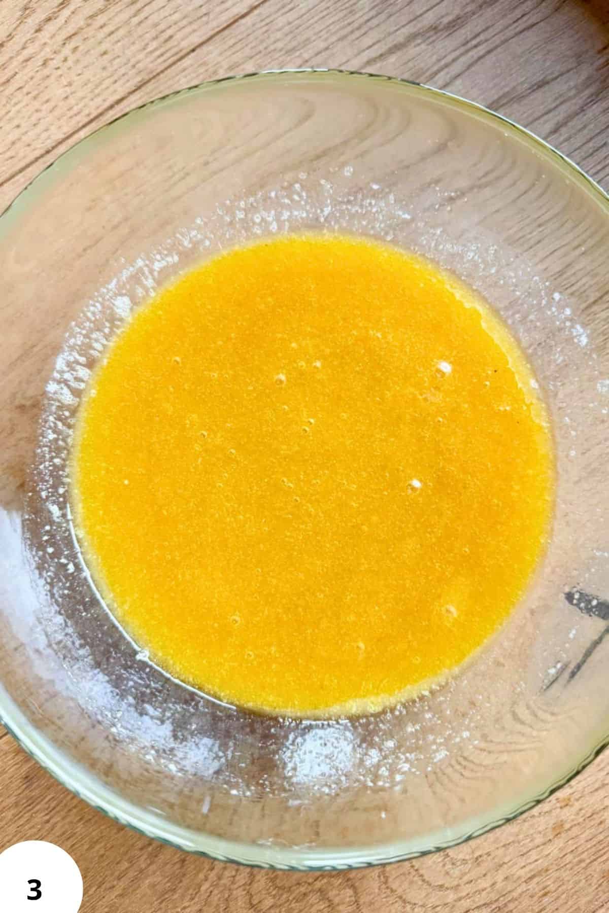 Bright yellow cookie dough in a glass bowl for baking.