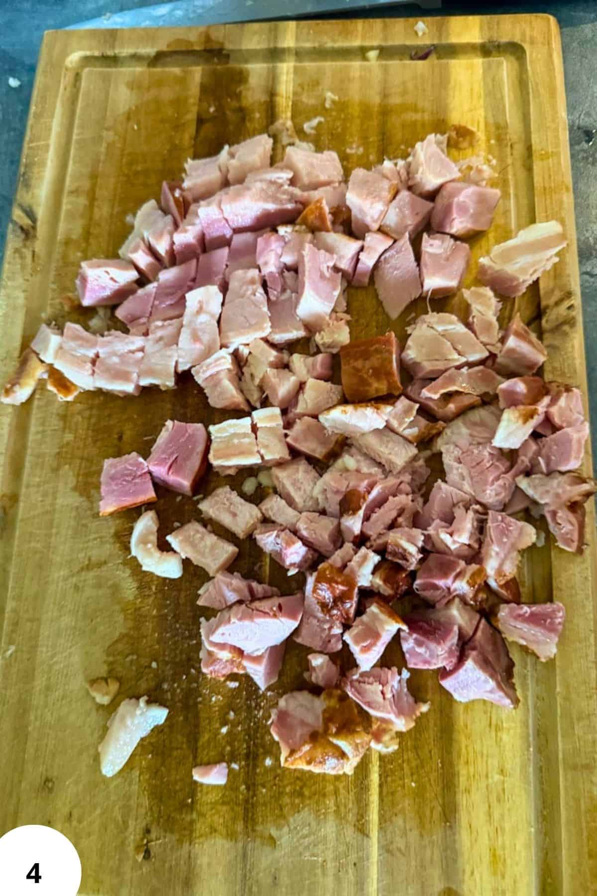 Diced smoked meat on a wooden cutting board for traditional Ričet stew.