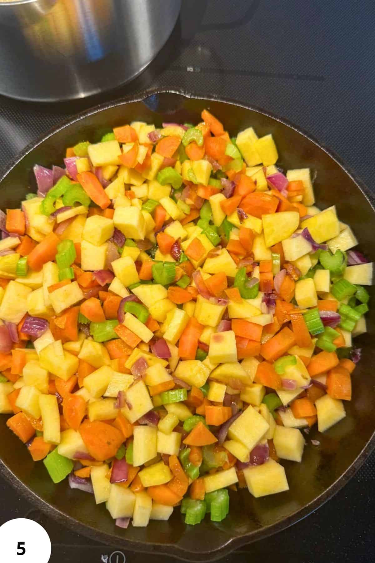 Assorted diced vegetables including carrots, potatoes, celery, and onions in a skillet.