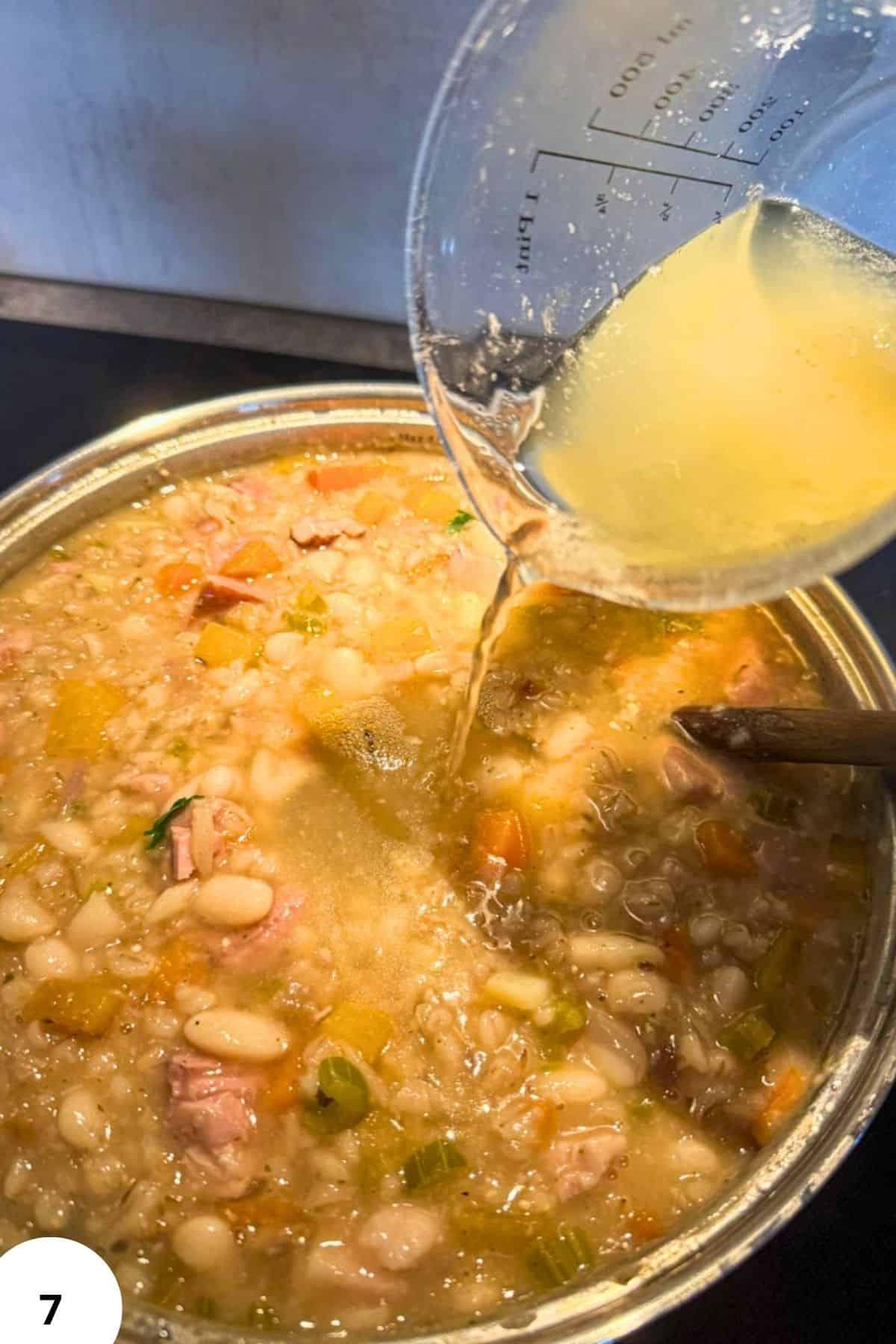 Cooking Ričet stew with barley, beans, and smoked meat in a pot.
