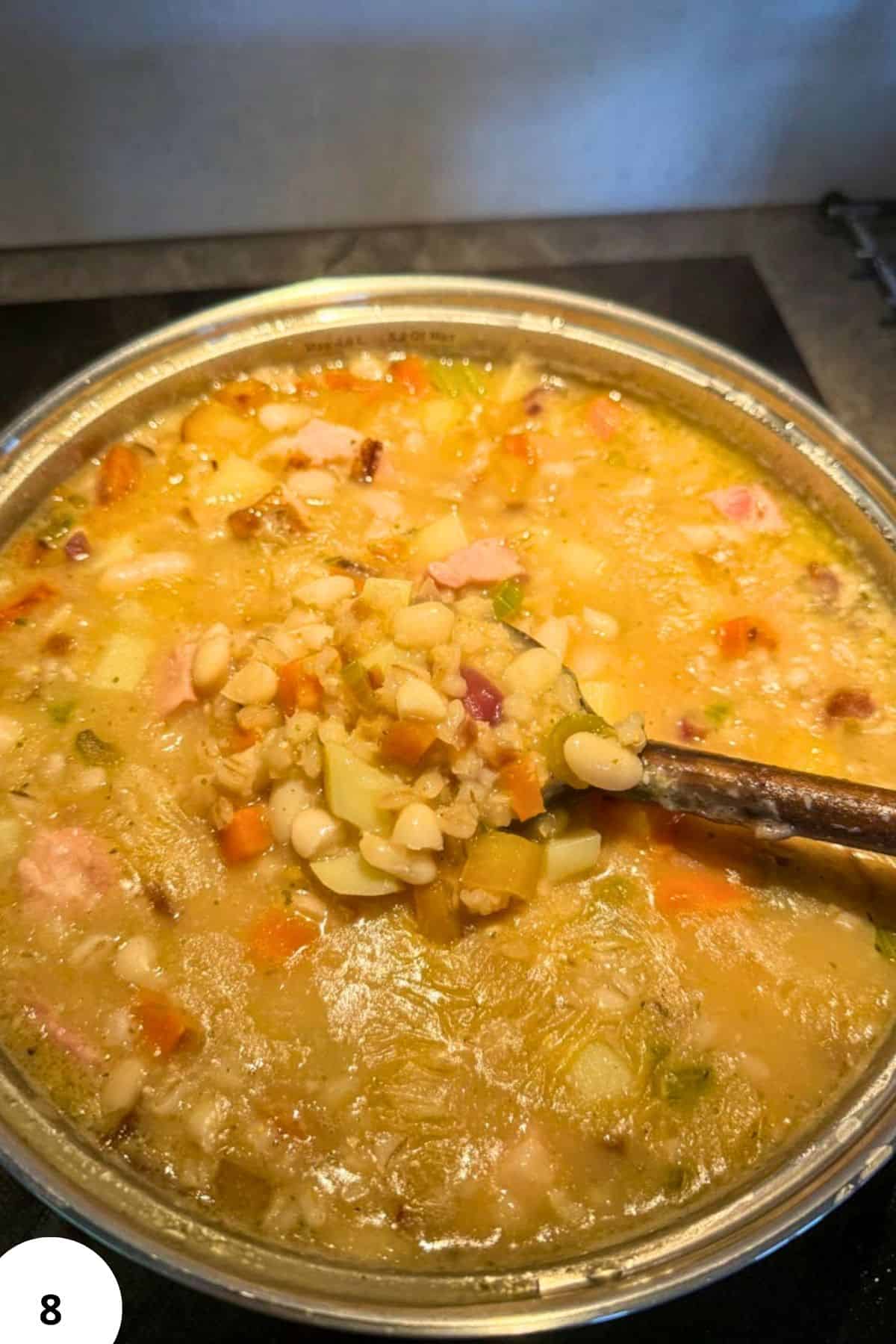Hearty barley and bean stew with smoked meat in a pot.