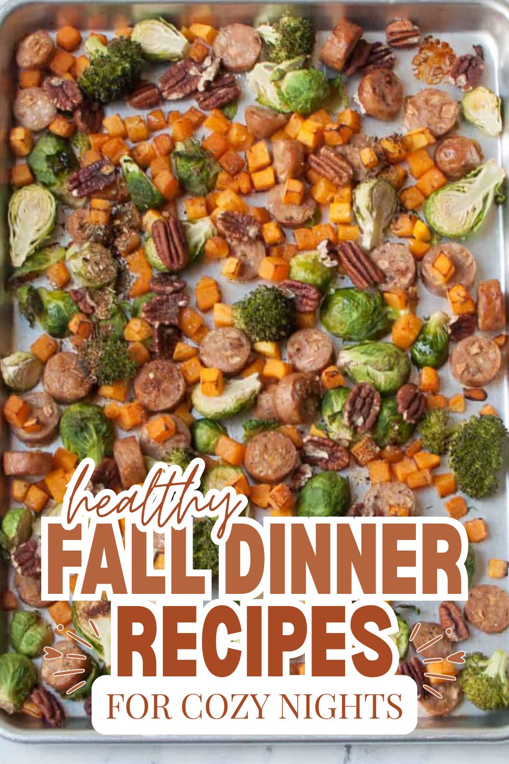 Colorful roasted vegetables and sausage on a baking sheet for fall dinner.