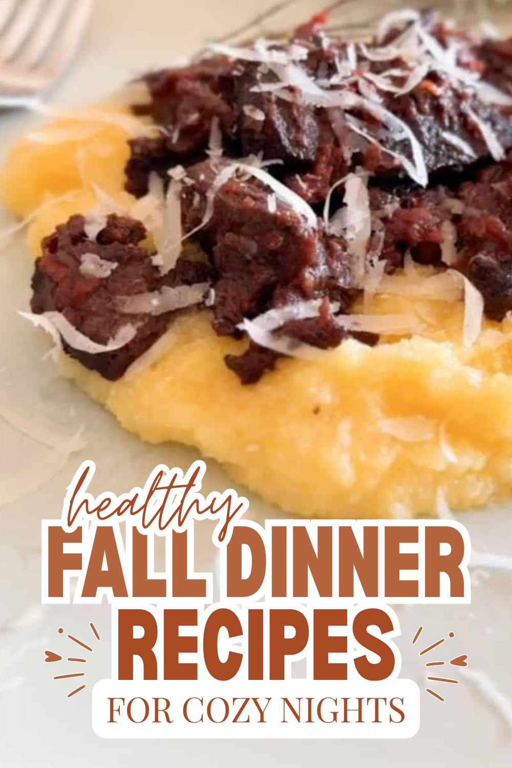 Close-up of hearty beef stew served over mashed potatoes with shredded cheese.
