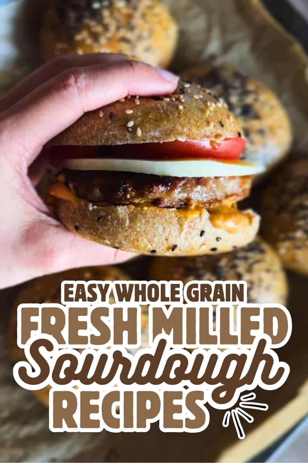 Close-up of a hand holding a homemade whole grain sourdough burger bun with toppings.