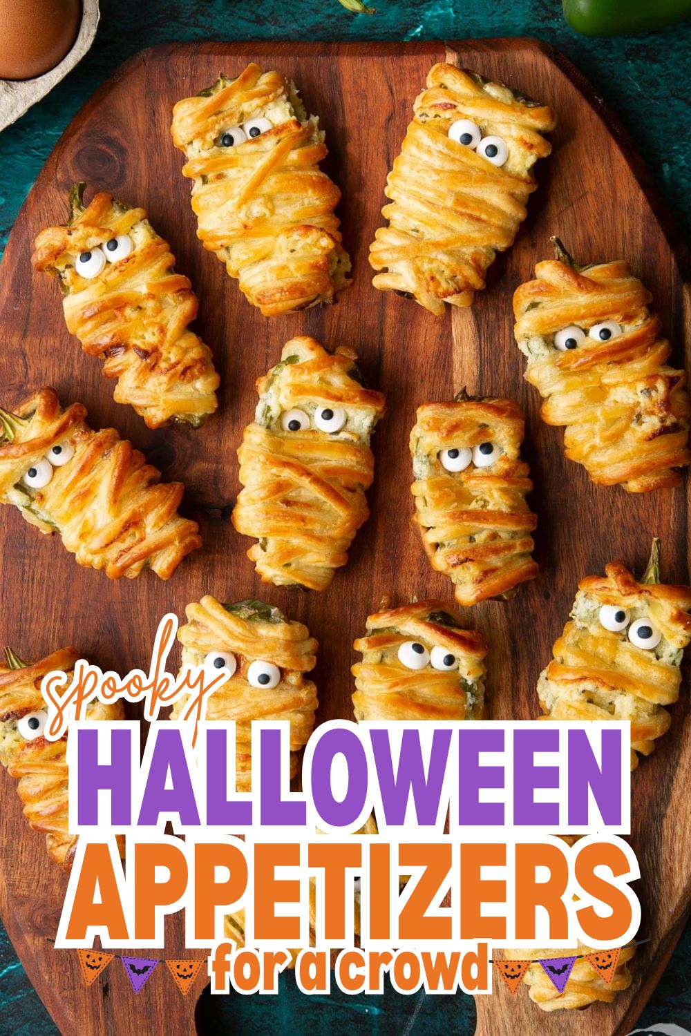 Spooky Halloween appetizers with googly eyes on a wooden platter.