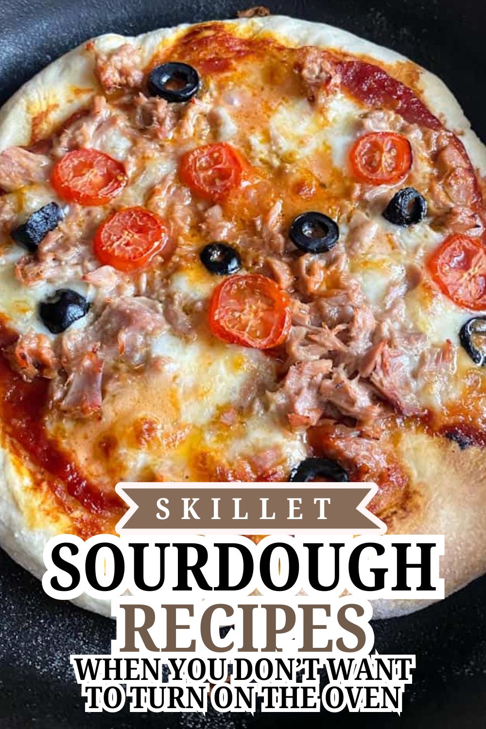 Close-up of a skillet sourdough pizza with cherry tomatoes and black olives.