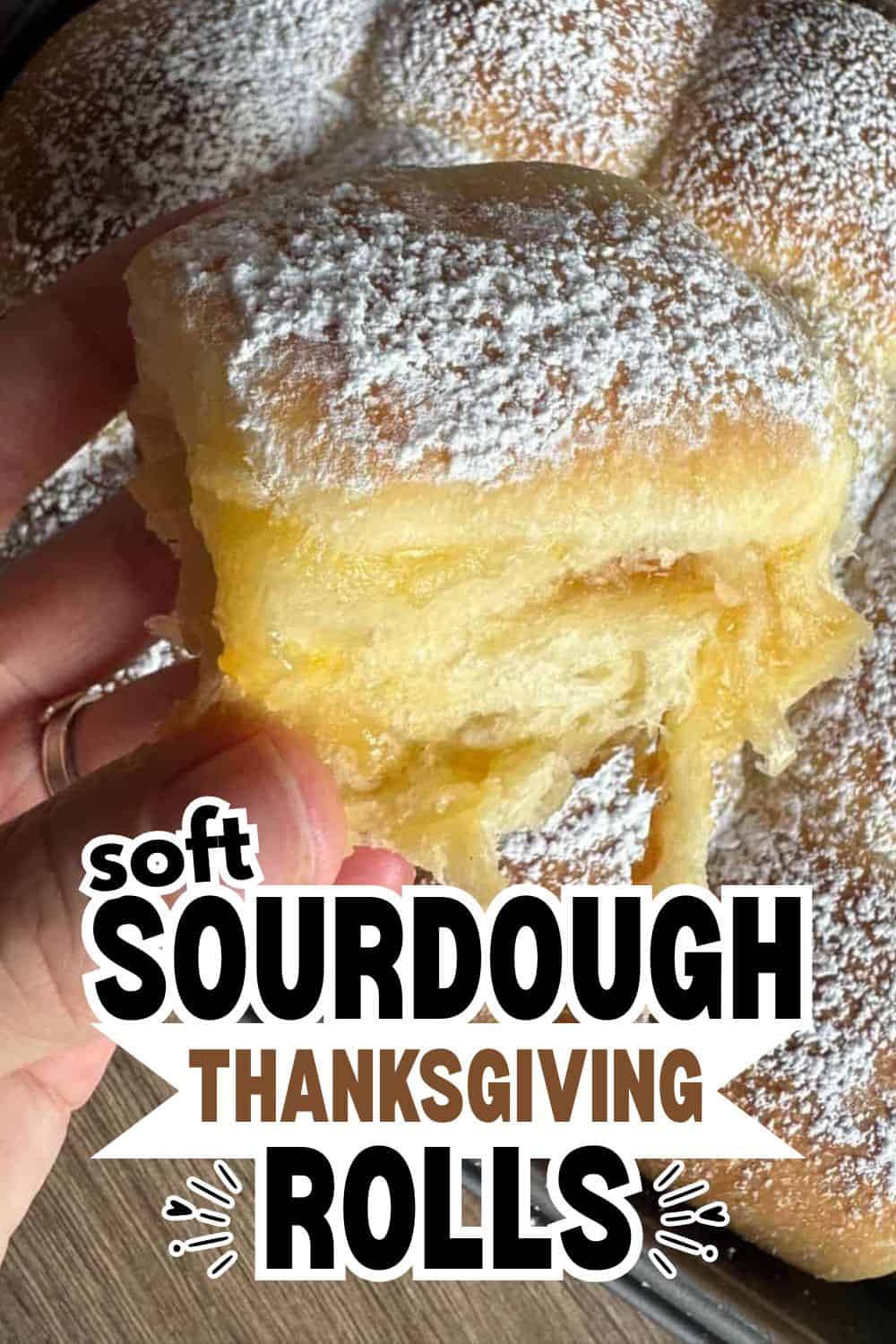 Close-up of soft sourdough Thanksgiving rolls dusted with powdered sugar.