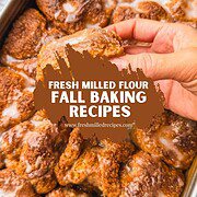 Close-up of hand holding a baked treat with fresh milled flour in background.