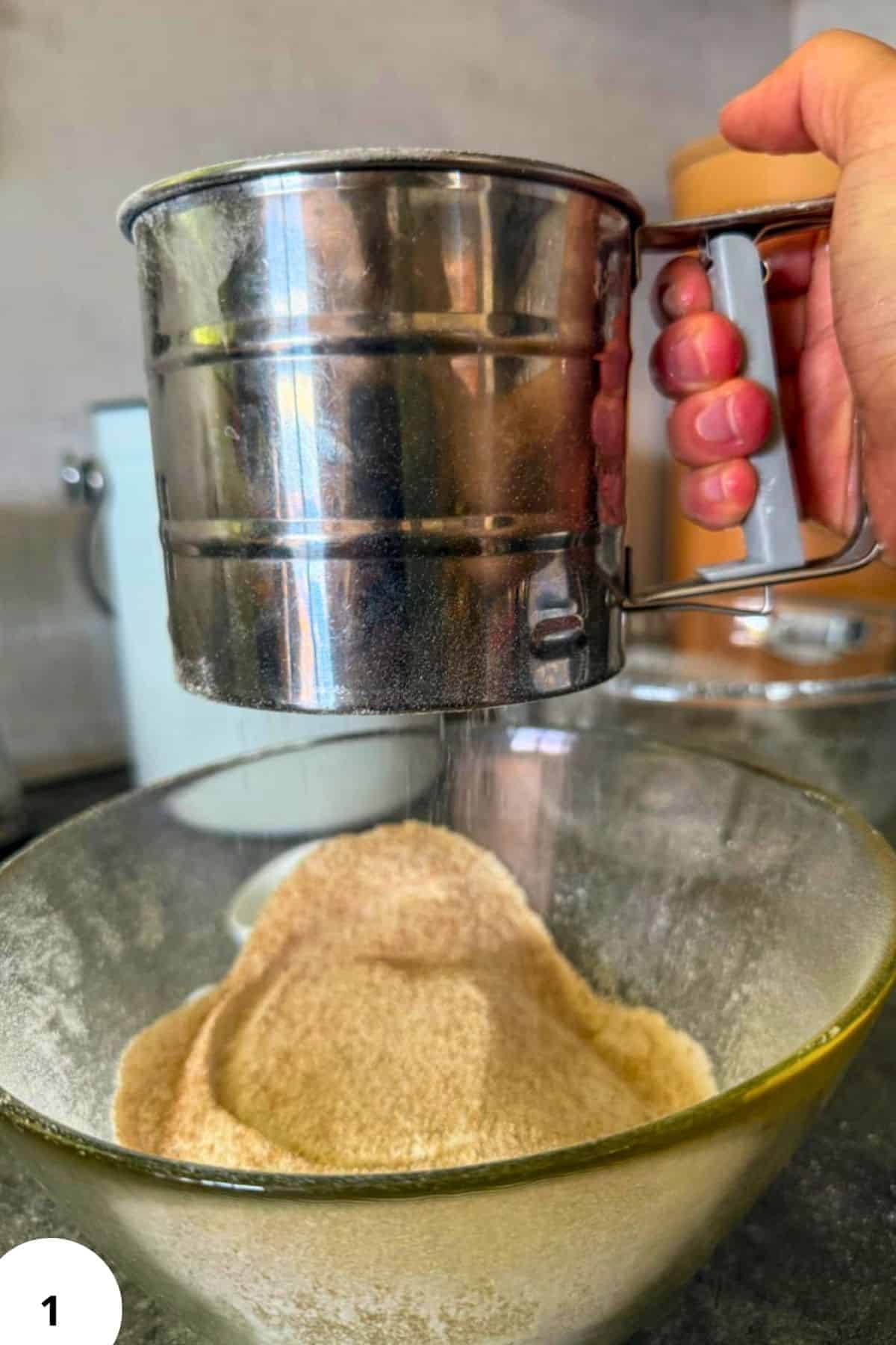 Hand sifting flour into a bowl for cherry strudel preparation.
