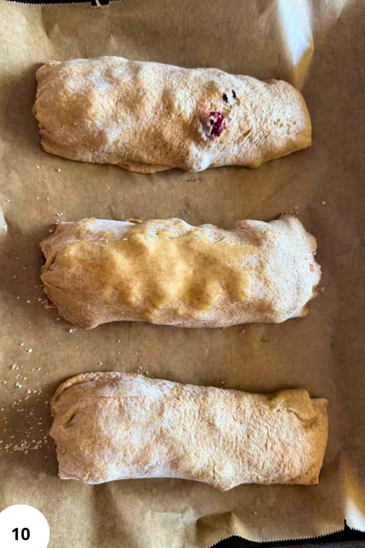 Three cherry strudel pastries dusted with powdered sugar on parchment paper.