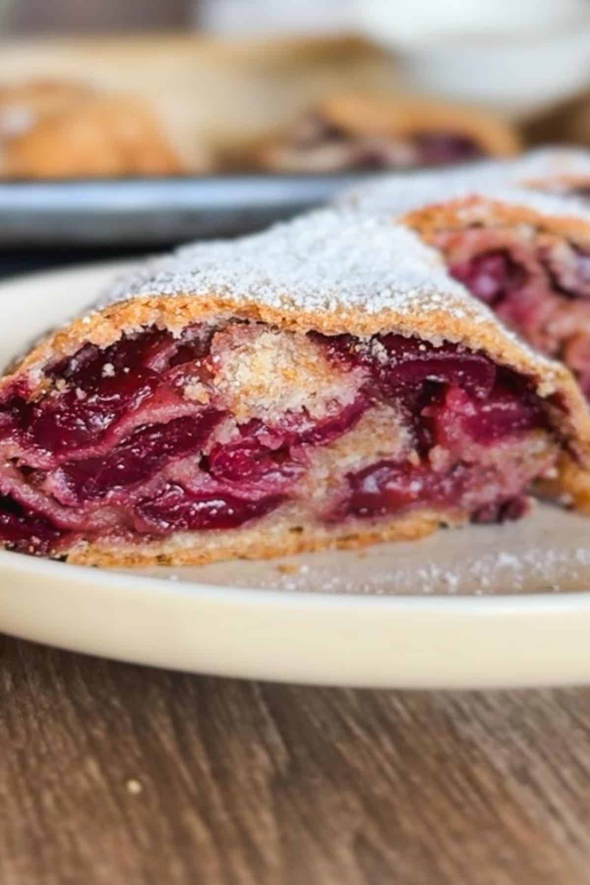 Close-up of cherry strudel with powdered sugar on top.