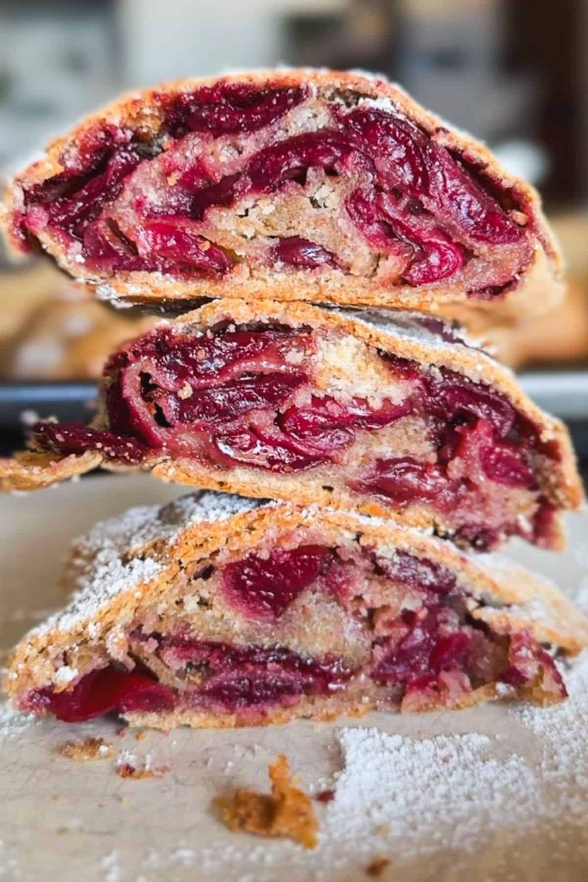Close-up of cherry-filled strudel with flaky crust and powdered sugar.
