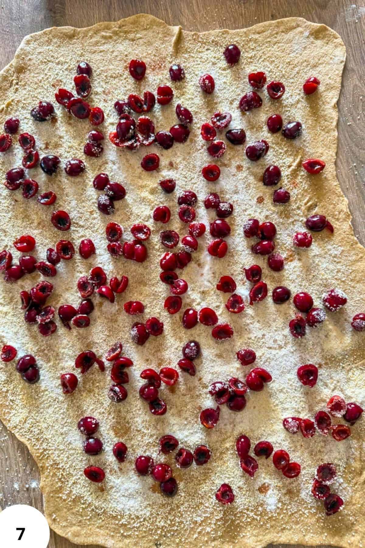 Unbaked cherry strudel with fresh berries and powdered sugar on dough sheet.