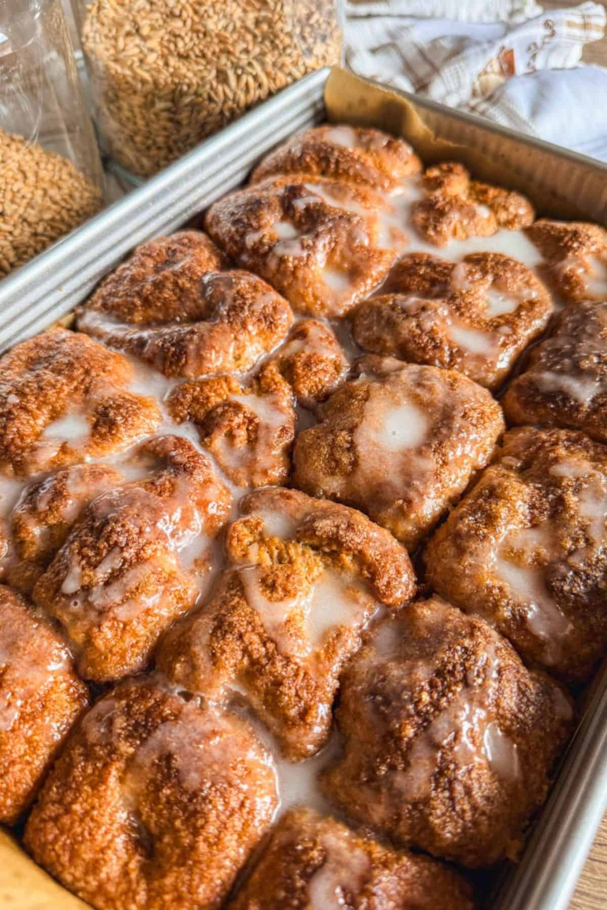 Close-up of cinnamon roll pull-apart focaccia with glaze in a baking dish.