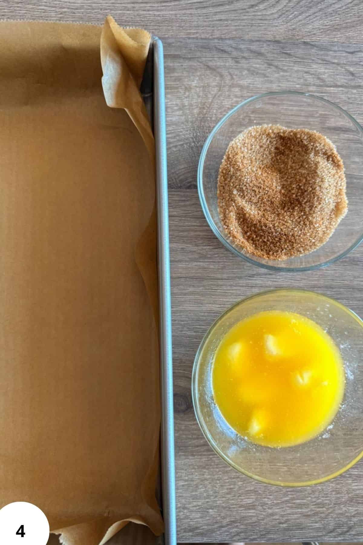 Ingredients for cinnamon roll focaccia with sugar, butter, and dough on a wooden surface.