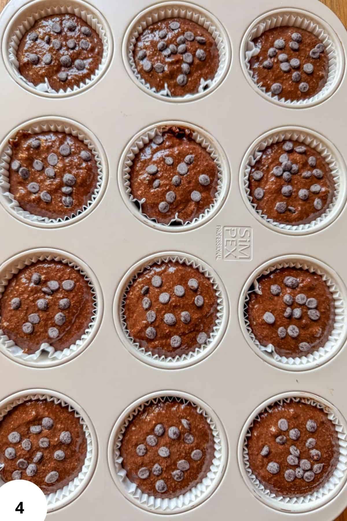 Chocolate zucchini muffins in a baking tray with sugar crystals on top.