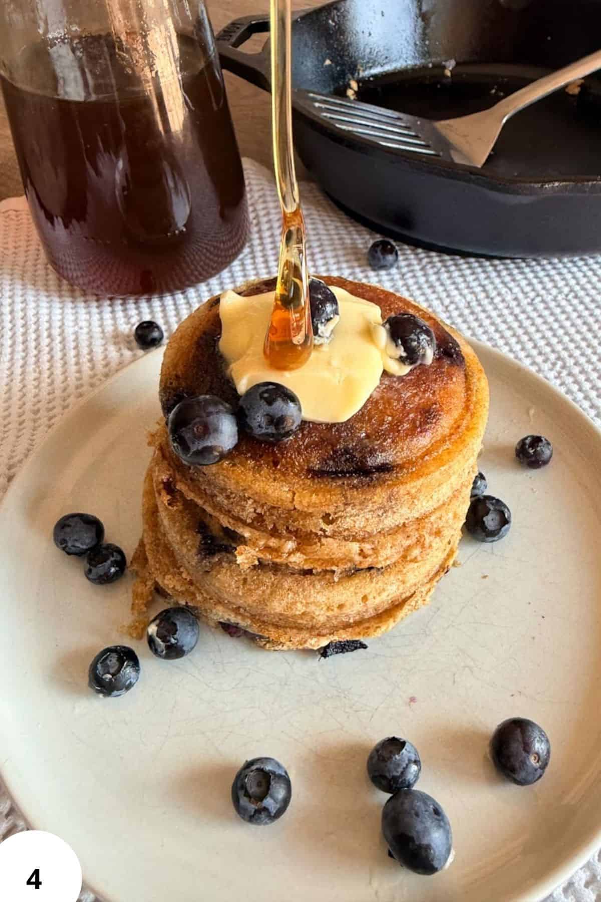 Stack of sourdough pancakes with blueberries and syrup on a plate.