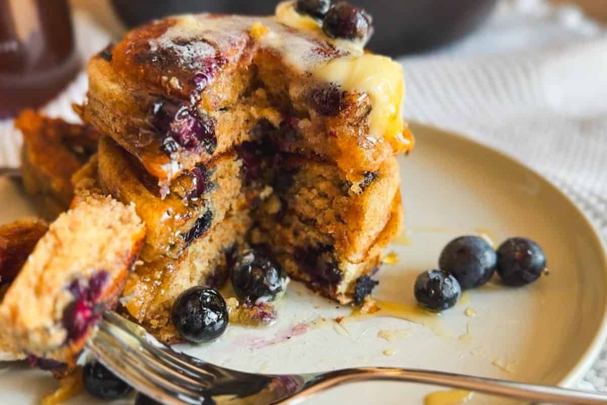 Close-up of blueberry sourdough mini pancakes with syrup and blueberries.