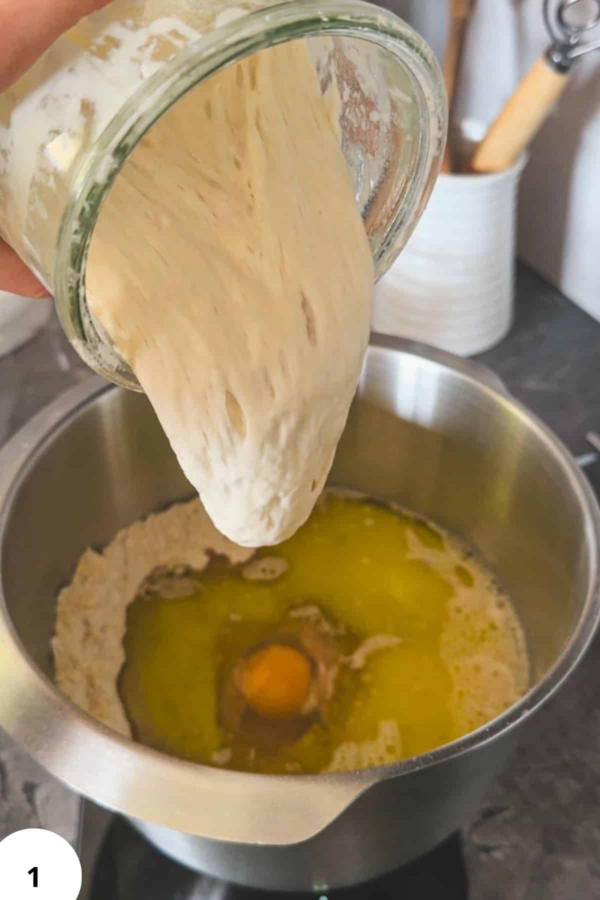 Pouring freshly milled sourdough dough into a mixing bowl for baking.