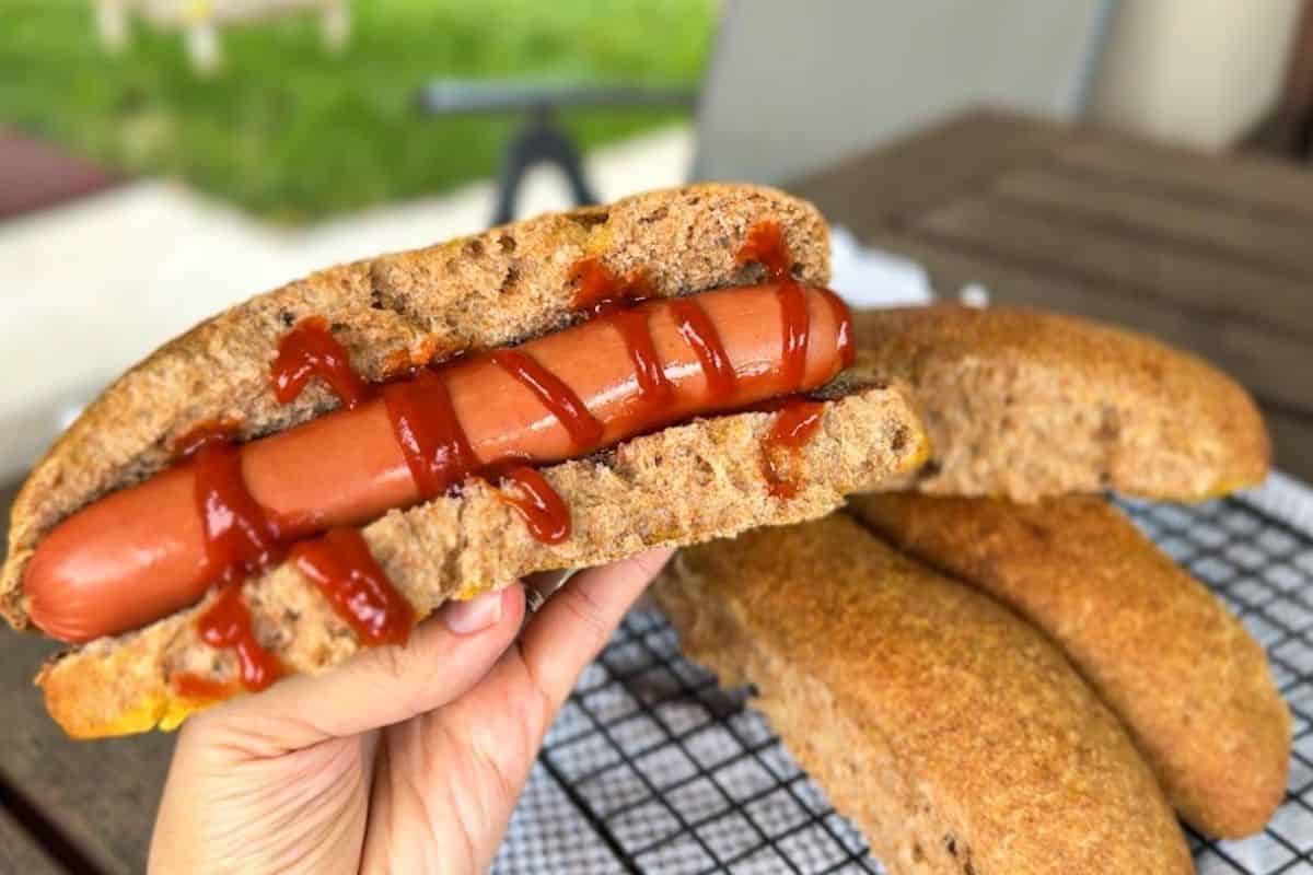 Close-up of freshly baked sourdough hot dog buns with sausage and ketchup.