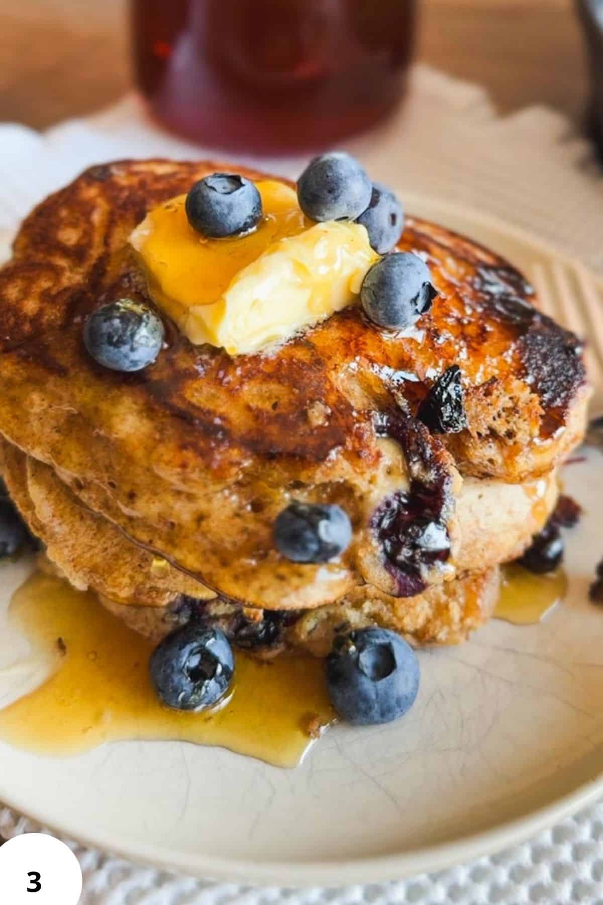 Close-up of sourdough pancakes topped with blueberries and butter.
