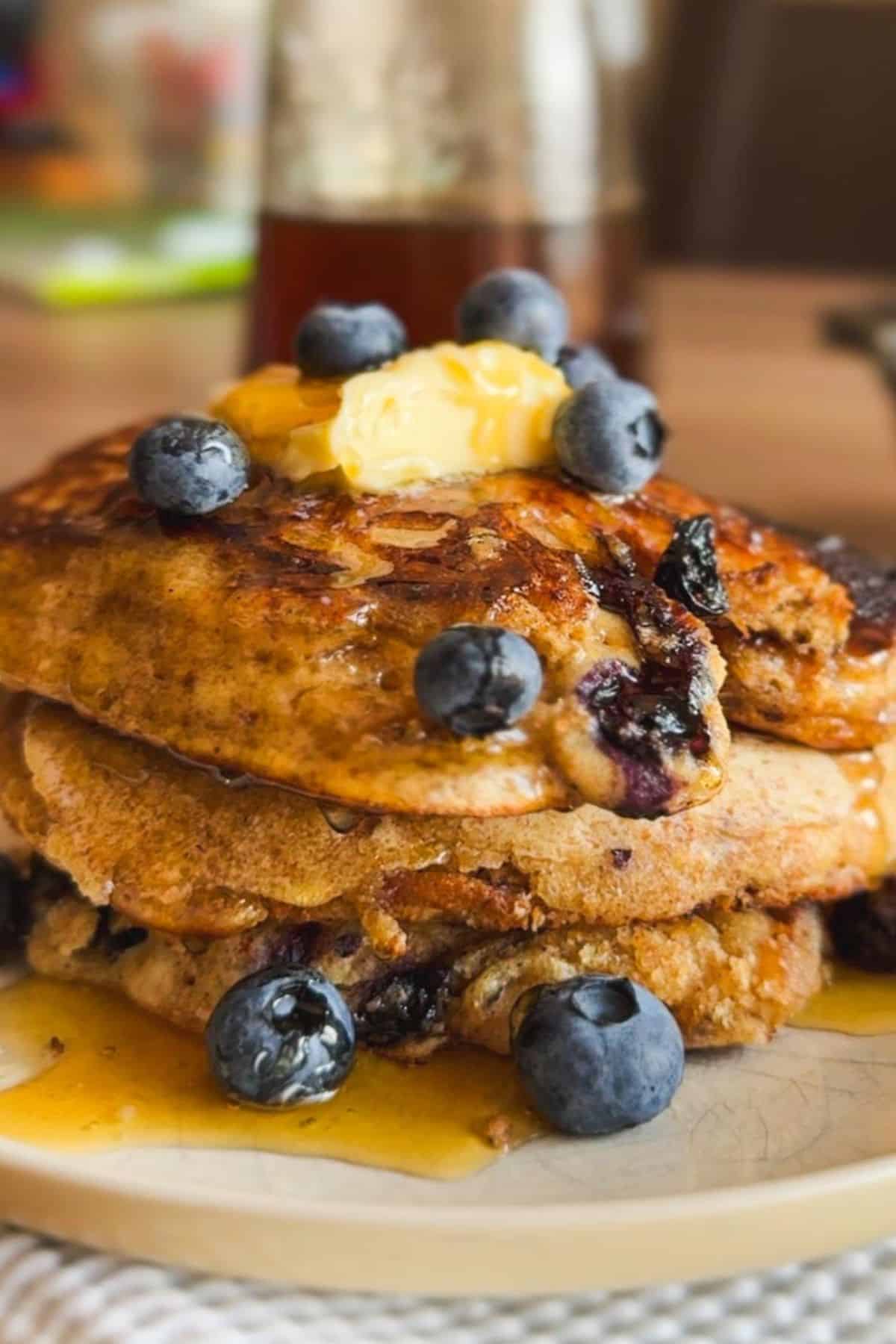 Stack of sourdough pancakes topped with blueberries and butter.
