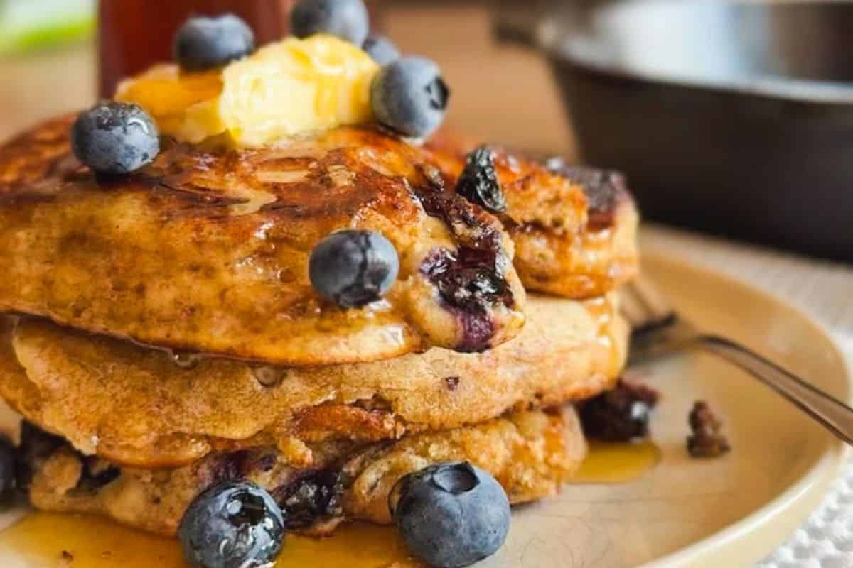 Close-up of sourdough pancakes topped with blueberries and butter.