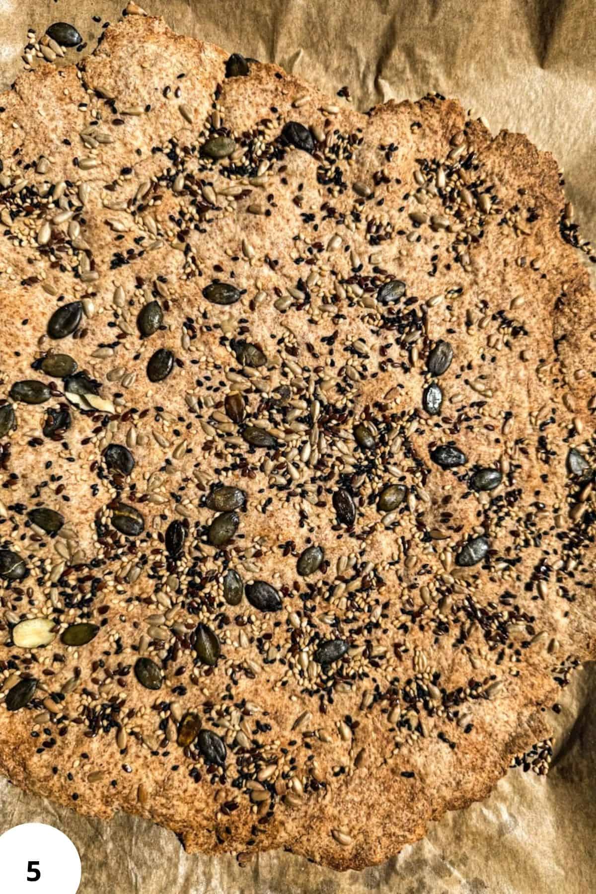 Close-up of crispy sourdough seed crackers with seeds on top.