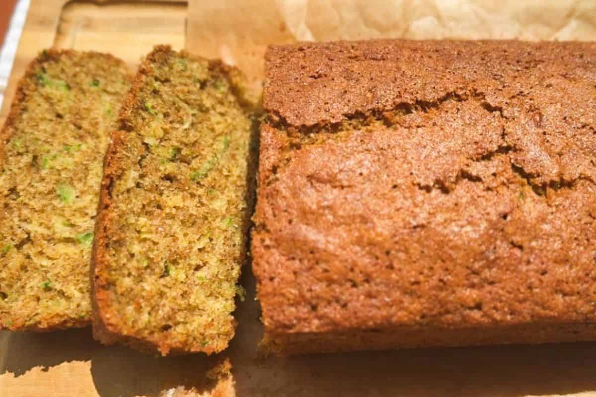 Homemade zucchini bread slices and loaf on a wooden surface.