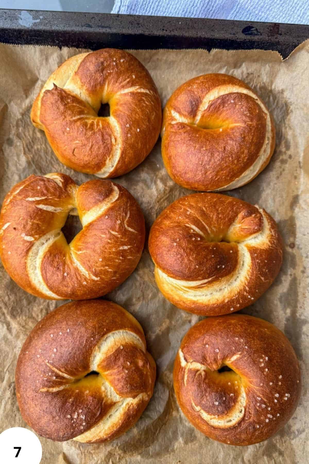 Six golden-brown bagels on parchment paper, ready to eat.