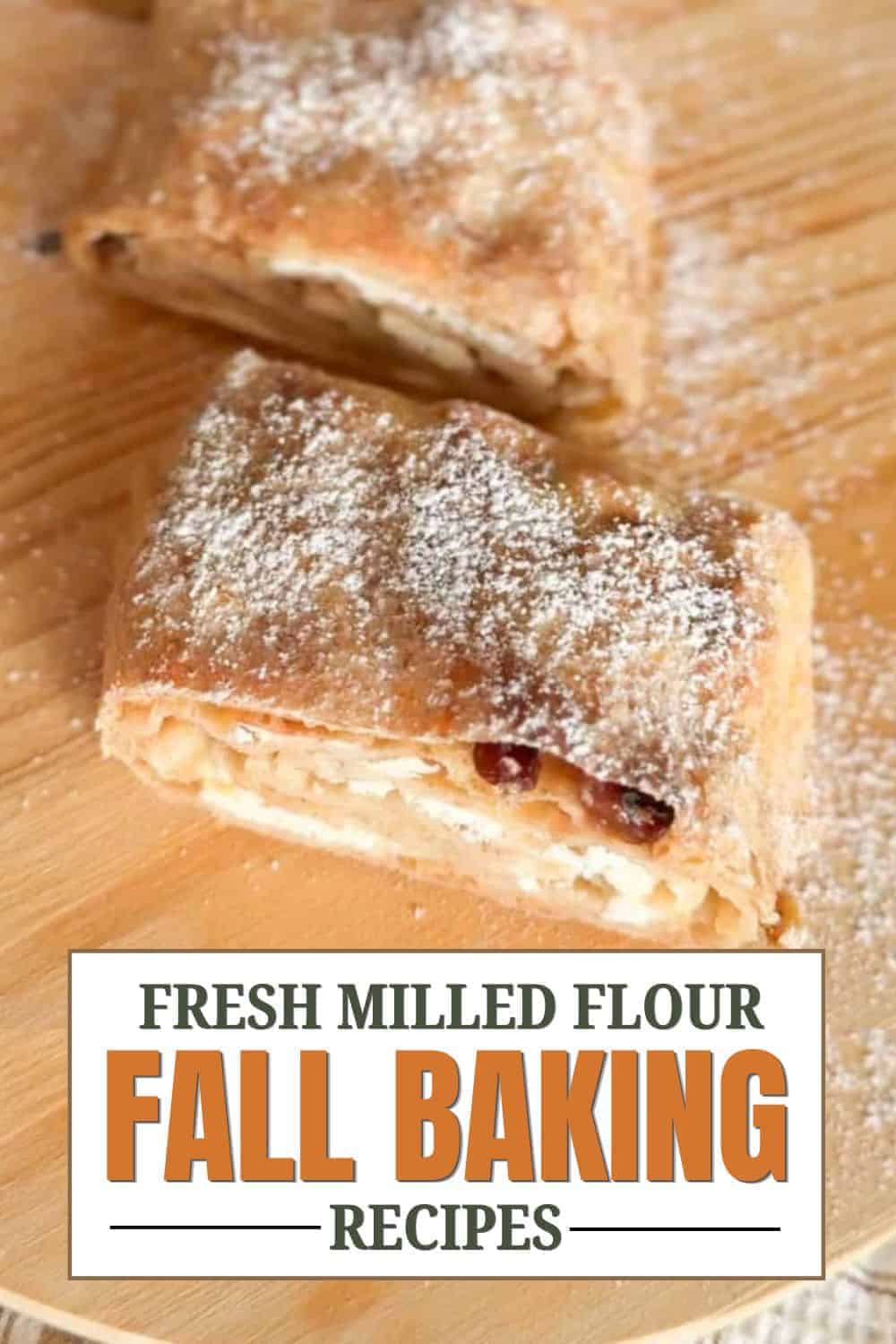 Close-up of baked pastry with powdered sugar on top, on a wooden surface.