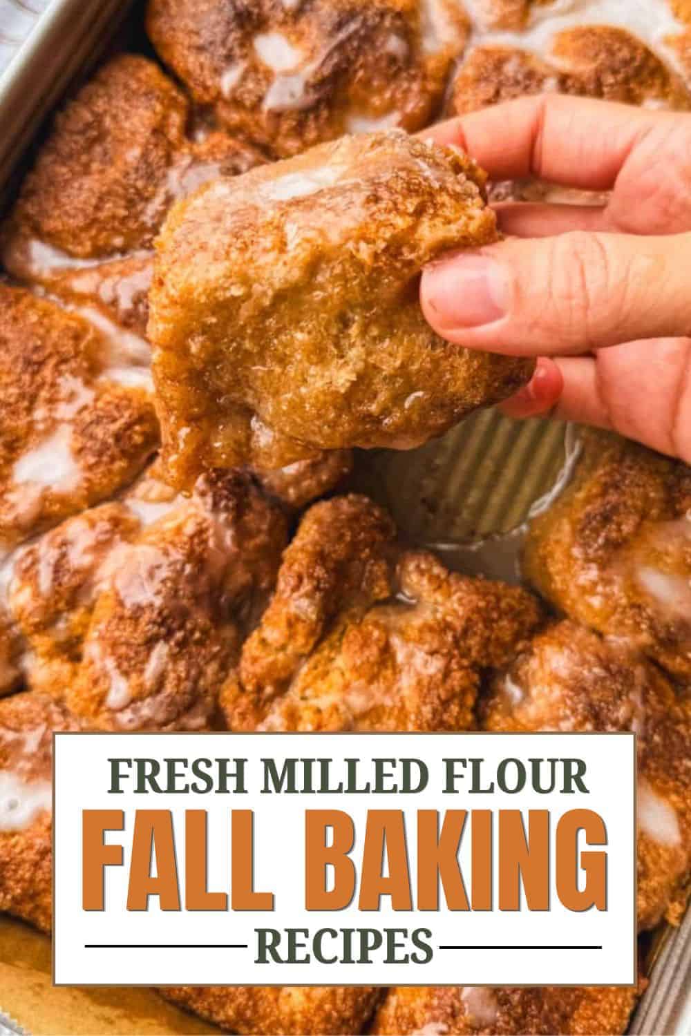 Close-up of a hand holding a piece of fried dough with baked goods in the background.