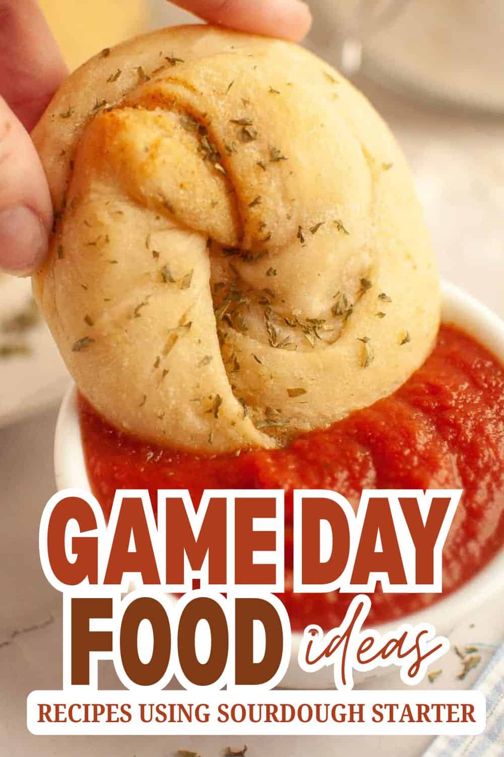 Close-up of a round sourdough bread with herbs, dipped in tomato sauce.