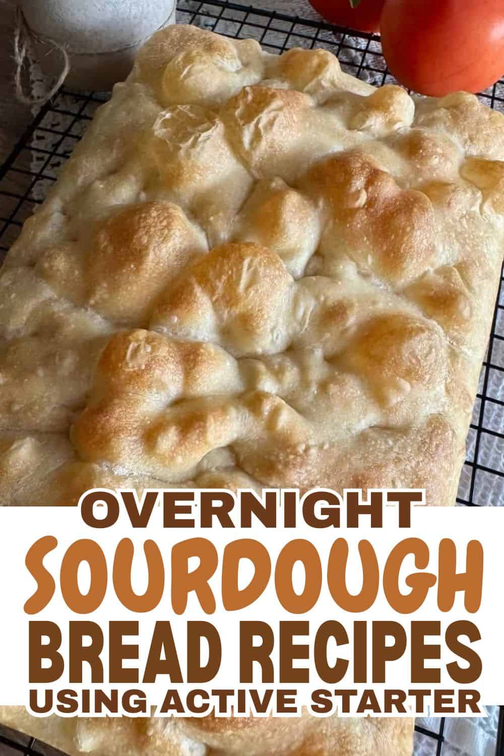 Freshly baked sourdough bread with bubbly crust on cooling rack.