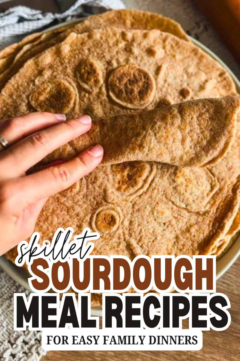 Close-up of sourdough bread with a hand touching the crust.