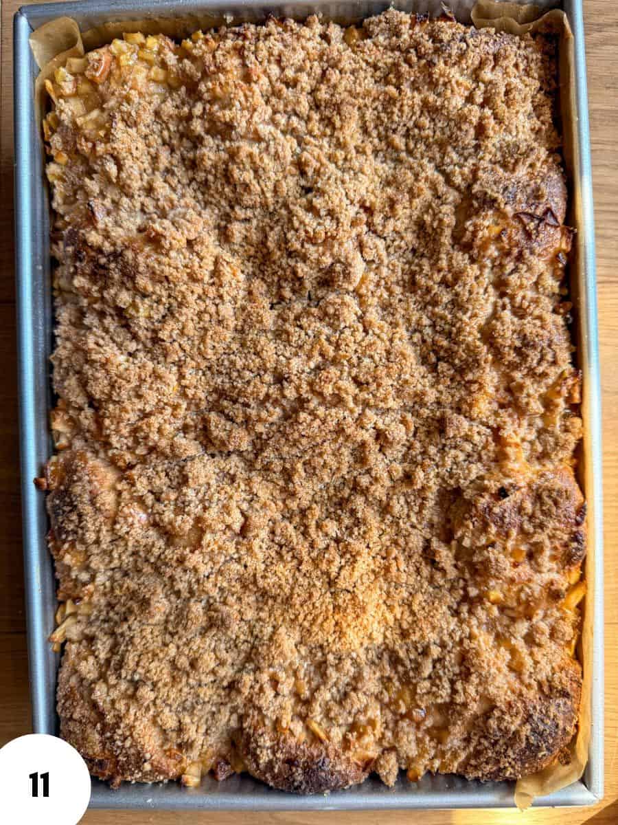 Apple cinnamon crumble focaccia with a golden, crumbly topping in a baking tray.