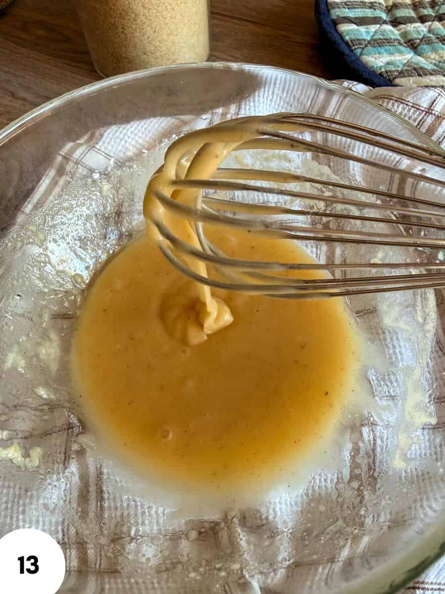 Mixing dough for bread with a whisk in a glass bowl.