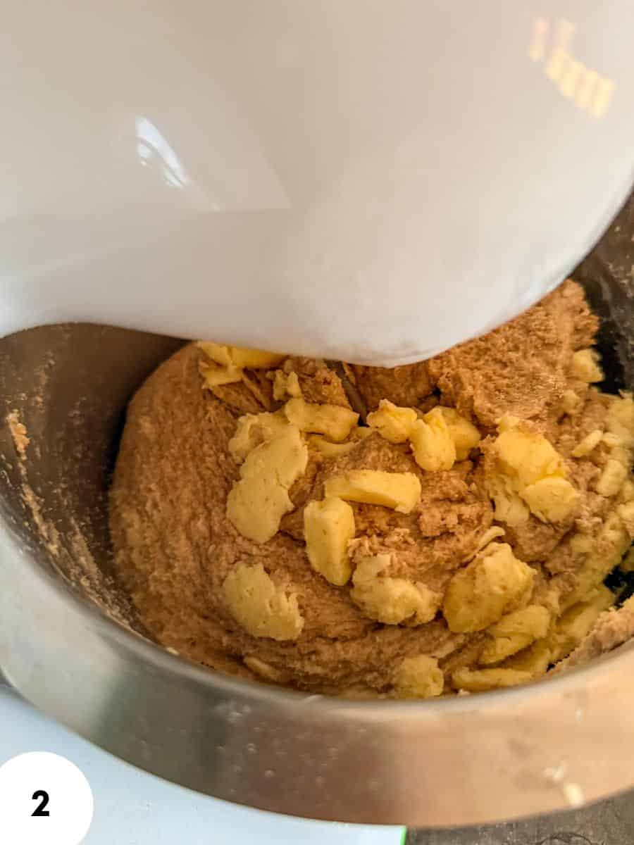 Dough being mixed with butter in a stand mixer for bread baking.