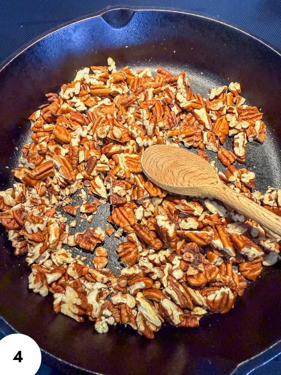 Toasted pecan pieces in a skillet for baking or snacking.