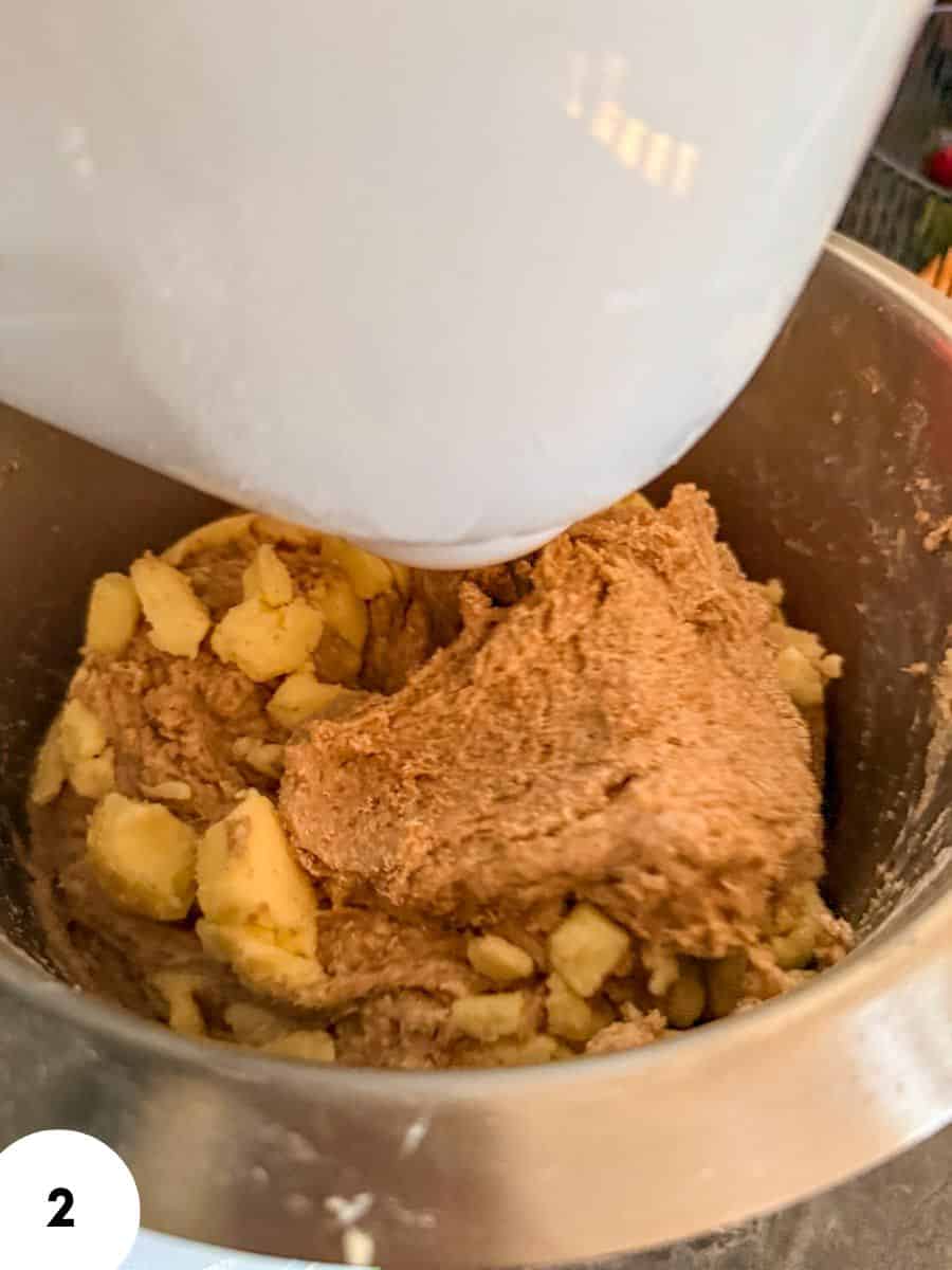 Dough and chopped ingredients in a stand mixer for bread making.