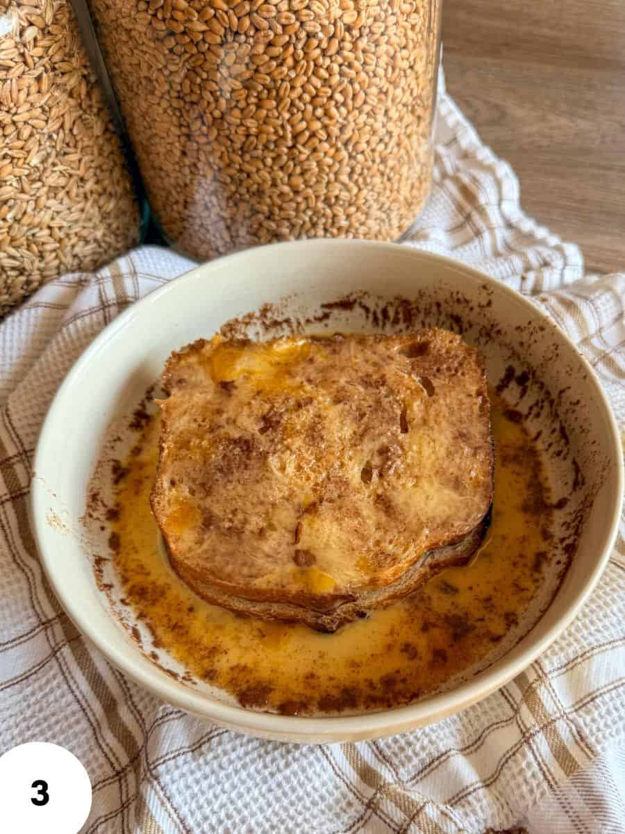 Freshly baked sourdough bread with honey butter in a white bowl.